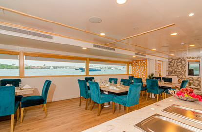 Salón Comedor del yate Sea Star Galápagos con varias mesas, sillas y cubiertos